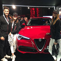 Event staff posing with a red Alfa Romeo Stelvio at a motor show launch &mdash; automotive event hostesses in New York
